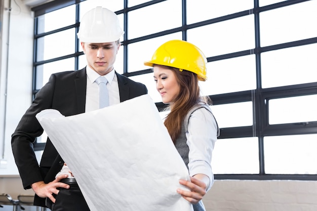 Architects looking at blueprint in office