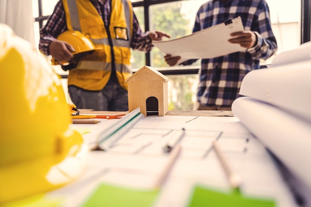 Architects talking at the table teamwork and workflow creation\
concepts closeup of person engineer\'s hand drawn plan on blue print\
with architect equipment