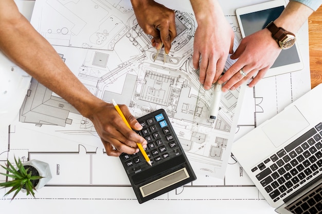 An architects working on architectural plan using calculator