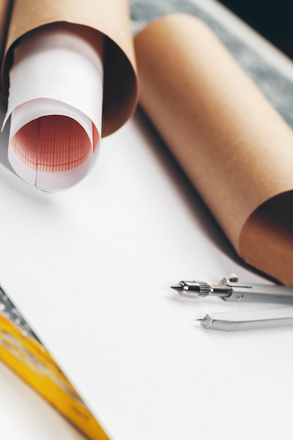 Architectural blueprints and blueprint rolls and a drawing instruments on the worktable.