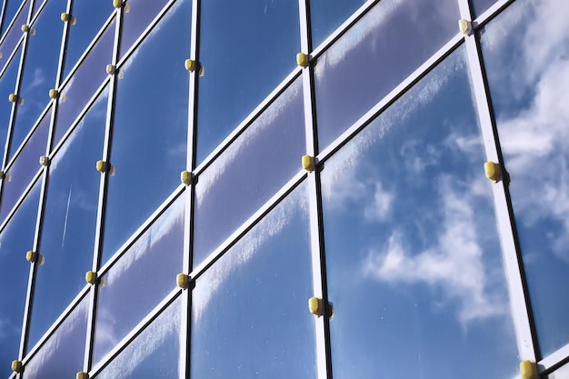 Architectural detail of the facade with multiple reflections of other buildings and the sun. Exterior of modern building. Architecture abstract background