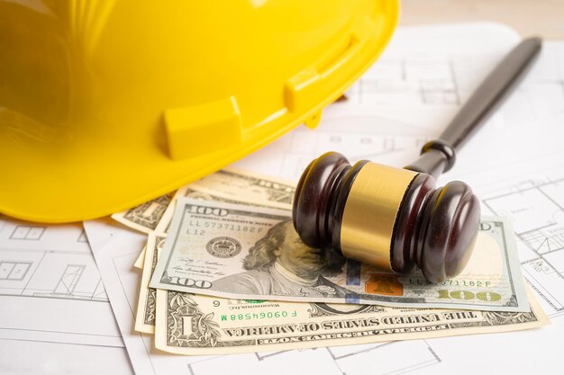 Photo architectural house plan project blueprint and judge gavel hammer with yellow helmet and us dollar banknotes engineer and construction law and justice