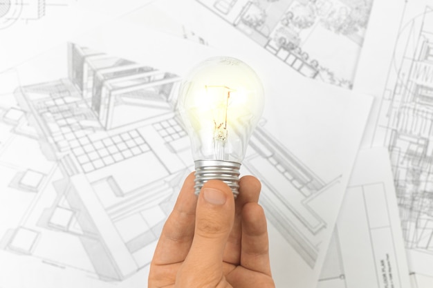 Photo architectural planning using blueprints, concept of success idea for construcion. man hold light bulb photo