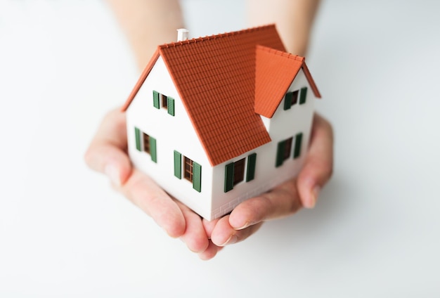 architecture, building, mortgage, real estate and people concept - close up of architect hands holding living house model