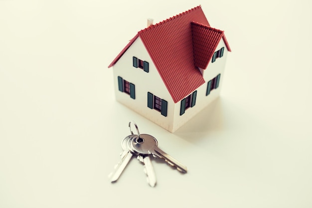 建築、建物、住宅ローン、不動産、不動産のコンセプト – 家の模型と家の鍵の接写