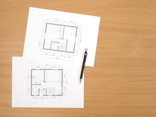 Architecture floor plan on paper is located on table with wood\
texture