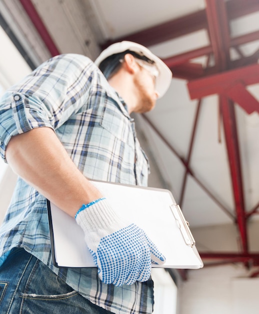 architectuur en huisvernieuwingsconcept - man in helm en handschoenen met blauwdruk in fabriek