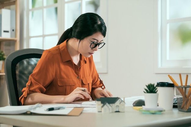 Architectuur jonge Aziatische vrouw werken blauwdruk werkruimte concept. succesvolle dame ingenieur zit aan bureau tekenen. vrouwelijke interieurontwerper in studio creatief dagdromen alleen brainstormen.