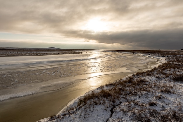 Photo arctic landscape in winter time. small river with ice in tundra.