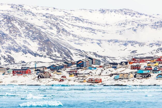 Foto arctisch sneeuwstadspanorama met kleurrijke inuit-huizen op de rotsachtige heuvels bedekt met sneeuw