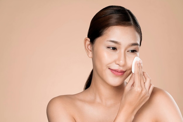 Ardent woman applying her cheek with dry powder while looking at camera