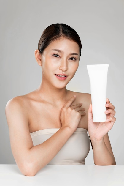 Ardent woman smiling holding mockup product for advertising text place light grey background Concept of healthcare for skin beauty care product for advertising