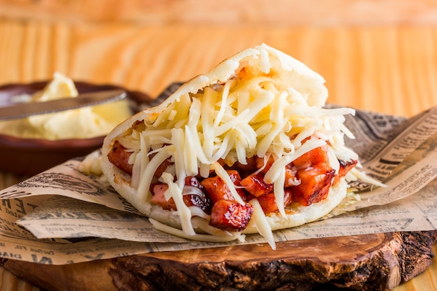 Arepa with fried pork and cheddar cheese ready to eat served on the table