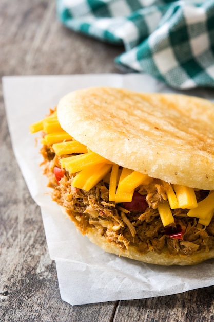 Photo arepa with shredded beef and cheese on wooden table venezuelan typical food