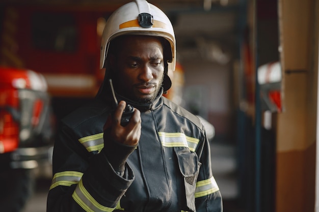 Arfican fireman in a uniform. Man prepare to work. Guy use radio transmitter.