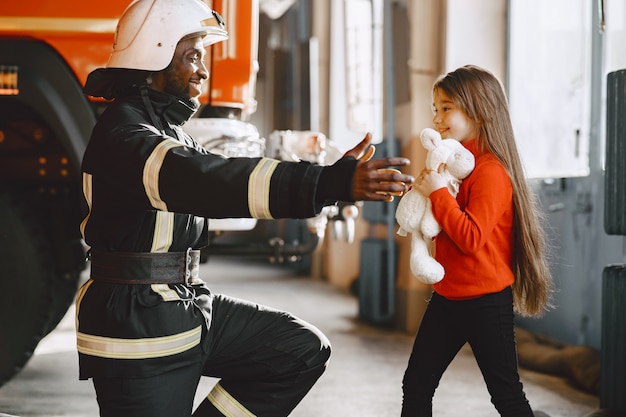 Arfican fireman in a uniform. Man prepare to work. Guy with child.