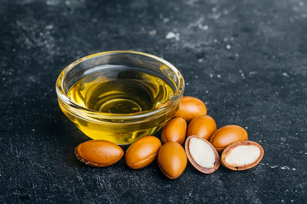 Argan seeds and oil on a dark wooden background