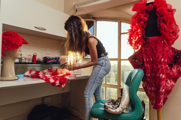 Argentine Caucasian young woman inside her atelier with black steel scissors cutting and sewing