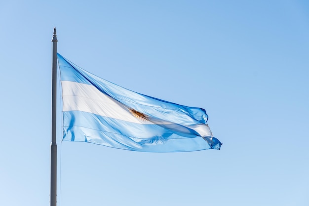 Аргентинский флаг на мачте, летящий в небе.