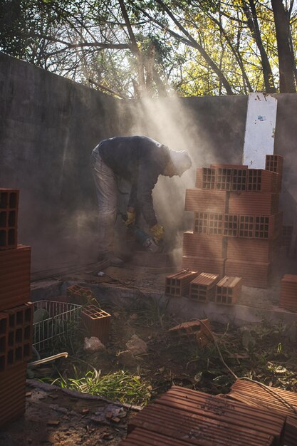 Argentine mason cutting brick with grinder among the dust