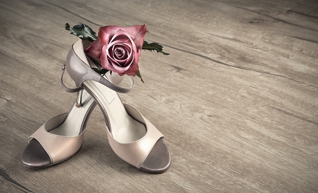 Photo argentine tango shoes and a rose on a wooden floor