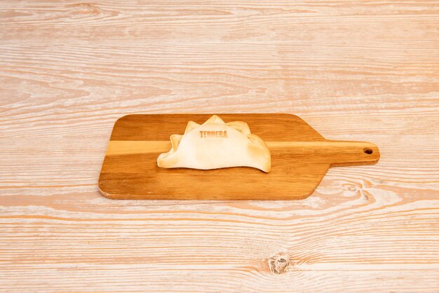 Argentinian empanada stuffed with beef stew on wooden board