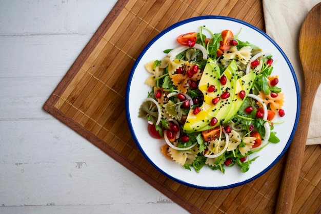 argula salad with pasta bows avocado cherry tomatoes pomegranate and sesame