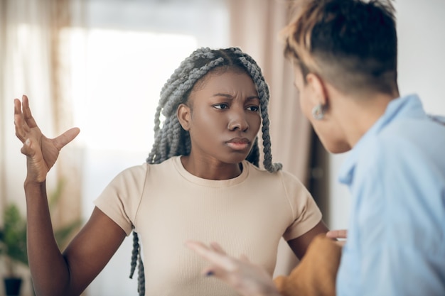 Argument. Dark-skinned girl talking to her girlfriend and looking agressive