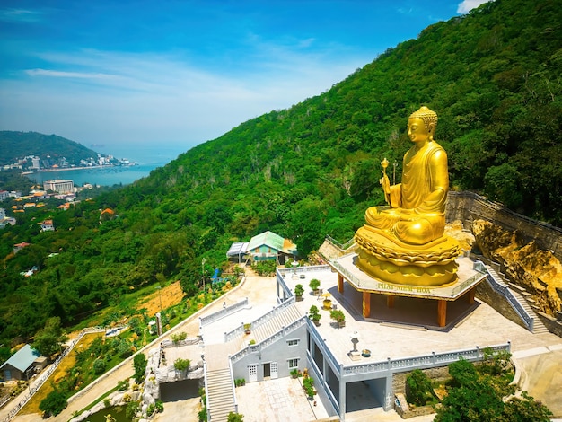 Фото Ариэль смотрит на статую золотого будды 39, держащую лотос в монастыре чон хонг, который привлекает туристов для духовного посещения по выходным в вунгтау концепция путешествия во вьетнаме