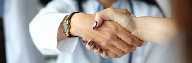 Foto braccio di medico femminile che stringe le mani con l'ospite