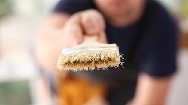 Arm of smiling worker hold brush closeup