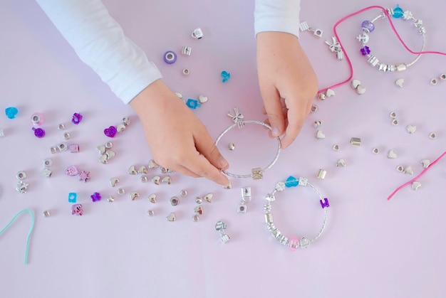 Armband is gemaakt door de handen van een kind uit een set voor creativiteit sieraden gemaakt van kralen aan de tafel in de kamer fijne motoriek ontwikkeling van kinderen close-up het concept van creativiteit van kinderen