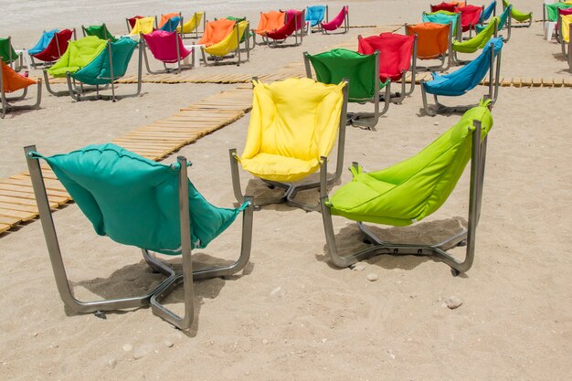 Armchairs with soft pillows on the sandy shore