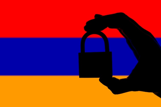 Armenia security Silhouette of hand holding a padlock over national flag