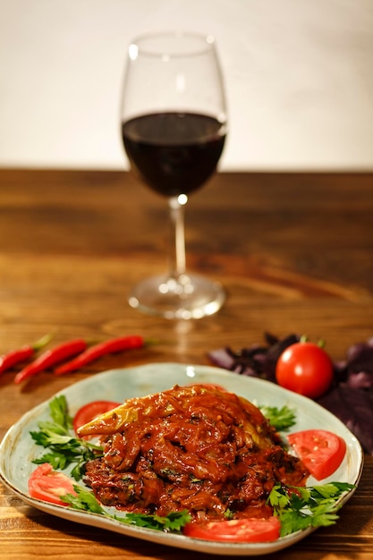 Armenian dish tjvjik or fried beef liver on wooden table with wine glass behind