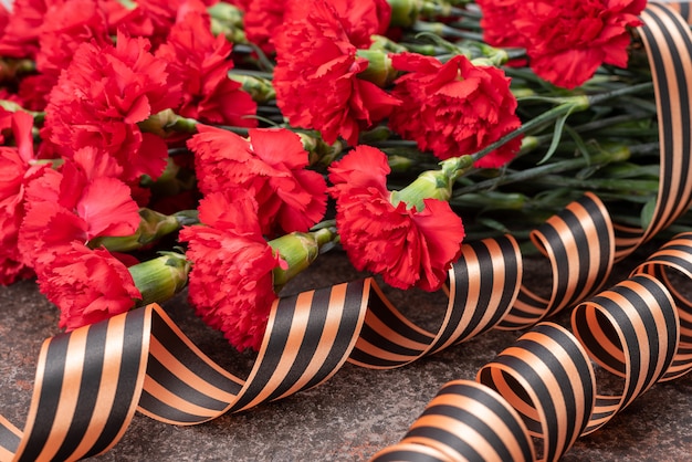 Photo armful carnations on dark background with ribbon