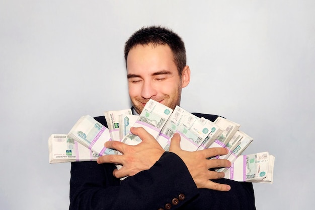 Armful of money in the hands of a young entrepreneur Rubles in packs Million rubles The winner of the lottery Joyful businessman The money fell into the hands