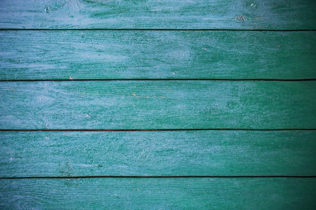 Armoedig en zeer oud groenblauw houten hekwerk.