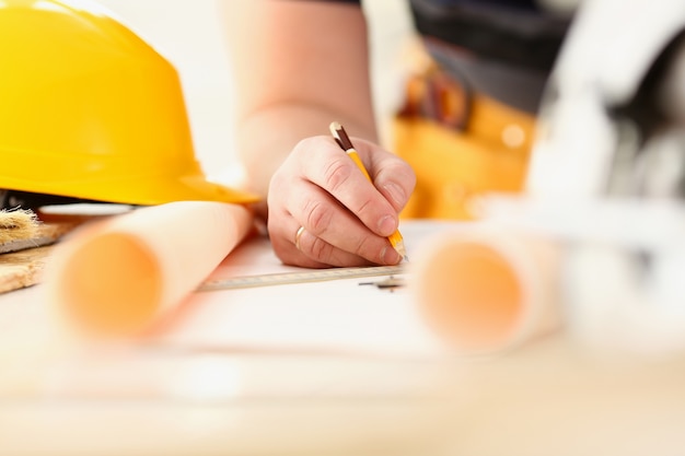 Arms of worker making structure plan on scaled paper