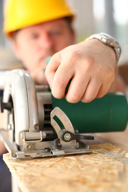 Arms of worker using electric saw