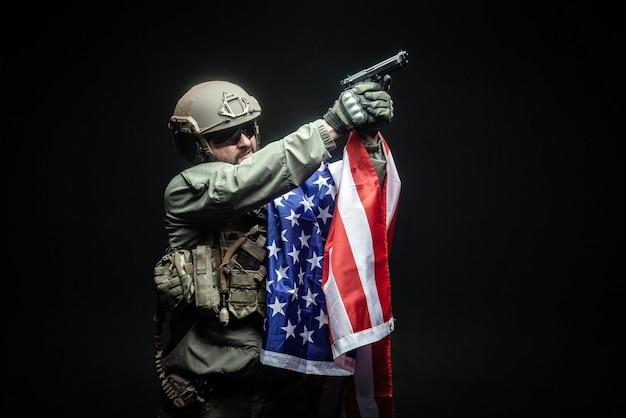 미국 육군 총을 든 군사 장비를 입은 군인이 미국 국기를 들고 있다
