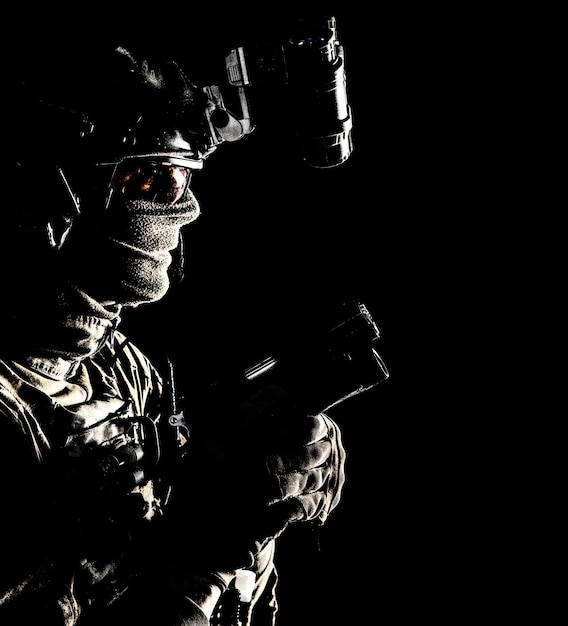 Army elite commando professional mercenary counterterrorist tactical team fighter in combat helmet equipped nightvision device creeping in darkness with service pistol in hand studio shoot