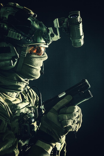 Army elite commando professional mercenary counterterrorist tactical team fighter in combat helmet equipped nightvision device creeping in darkness with service pistol in hand studio shoot