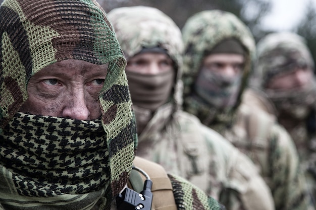 Фото Солдаты тактической группы армейских элитных сил, опытный отряд коммандос, члены в камуфляжной форме, скрывающие лица за масками, стоящие в очереди за командиром