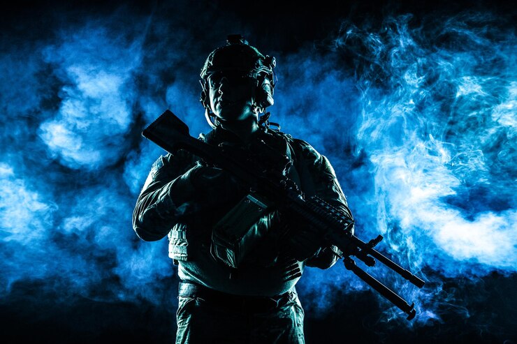 機関銃、プレートキャリア、戦闘用ヘルメットを着用した戦闘服を着た陸軍兵士がいます。スタジオ輪郭シルエットショット、バックライト、暗く輝く煙の背景