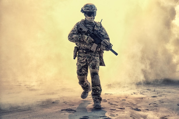 army soldier in military camouflage uniform, helmet, with face hiding behind mask and glasses, running out from fire. infantry rush with fire support, commando attack and breakthrough on battlefield