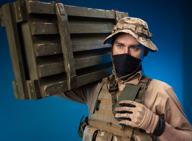 An army soldier in military clothes with a box of ammunition on\
his shoulder