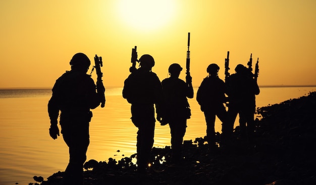 Army soldiers with rifles orange sunset silhouette