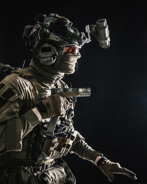 Army special operations soldier security service fighter commando shooter equipped modern ammunition wearing combat helmet mask and glasses carefully sneaking in darkness with handgun in hand