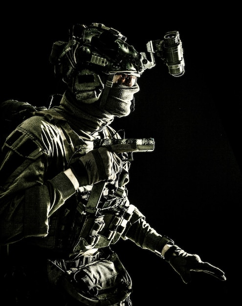 Army special operations soldier security service fighter commando shooter equipped modern ammunition wearing combat helmet mask and glasses carefully sneaking in darkness with handgun in hand